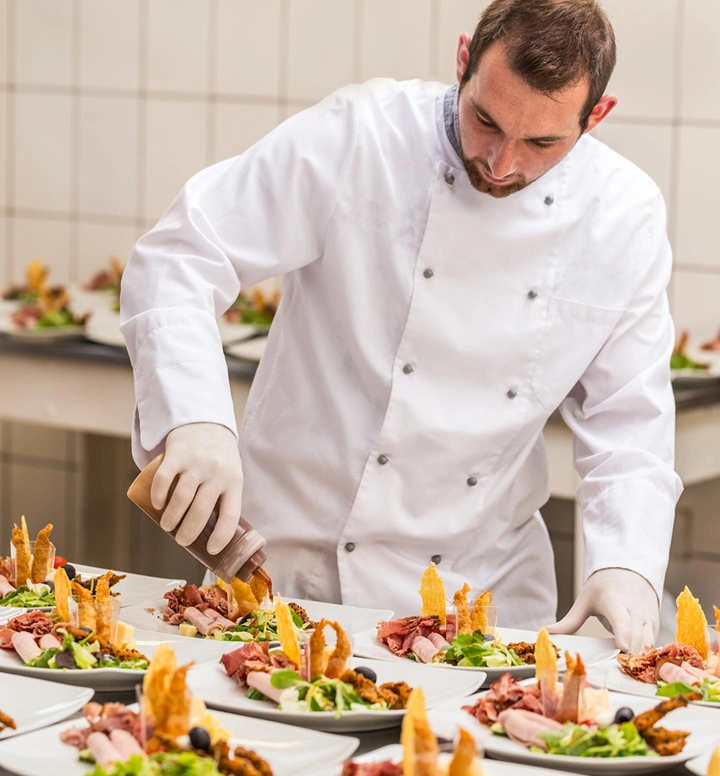Chef bereidt en presenteert meerdere gourmetgerechten in een professionele keuken tijdens een cateringservice