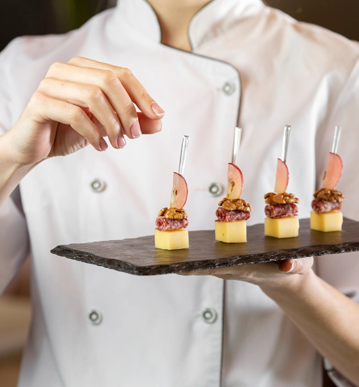 Chef presenteert elegante mini-canapéhapjes gerangschikt op een zwart serveerbord voor een verfijnde cateringpresentatie