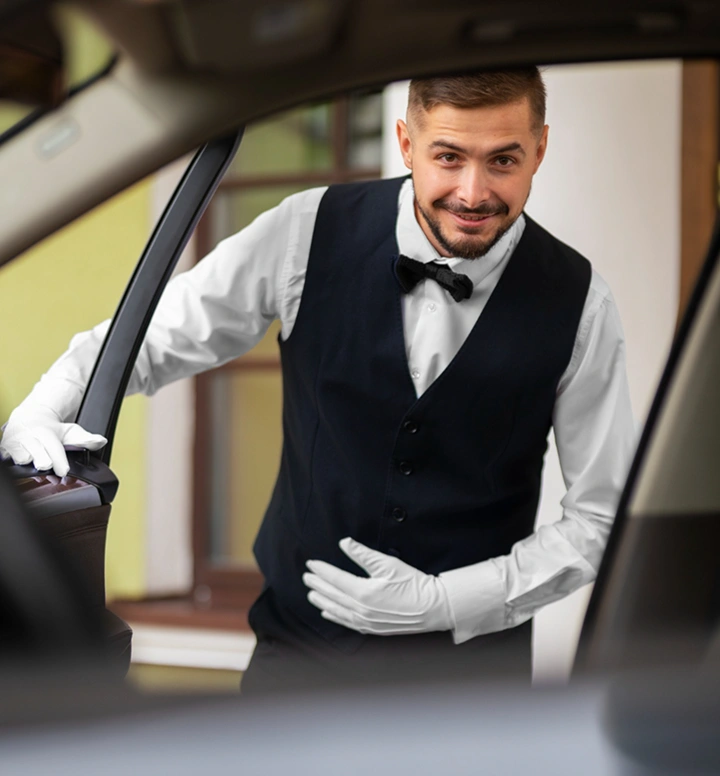Professionele chauffeur in formeel uniform opent een autodeur als onderdeel van premium gastvrijheidsservice